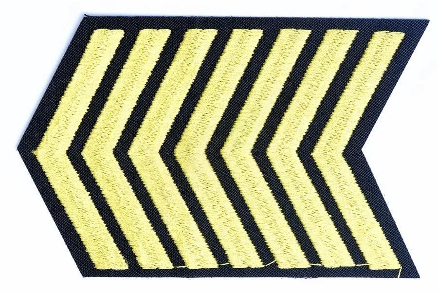 Фото товара-кандидата БлокПОСТ, артикул 87857: Нашивка вышитая Курсовка 7 курс. На фото курсовая нашивка: 7 золотистых угольников на тёмной основе; число угольников проверено визуально. Поворот товара на фото не является схемой ношения. Геометрия, размеры и допуск для конкретного ведомства остаются неподтверждёнными. Это не нормативный рисунок и не подтверждение соответствия уставу.
